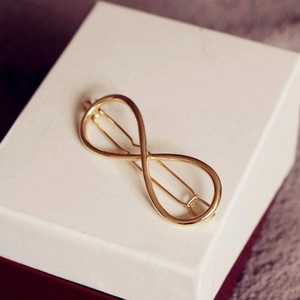 Minimalist infinity symbol metal hair clip in gold finish on a white jewelry gift box
