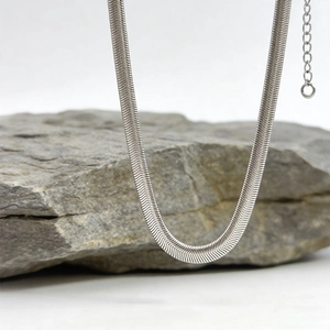 Collier maille serpent plate argentée polie sur pierre grise avec arrière-plan blanc