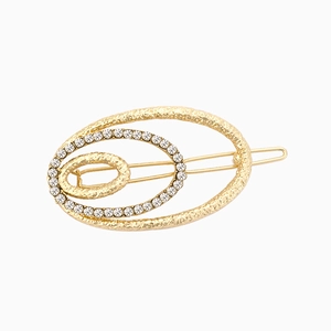 Dettaglio di un fermaglio geometrico triplo ovale dorato con strass e texture in metallo martellato