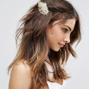 Close-up of a sparkling gold leaf hair clip with crystals on a woman's brown hair