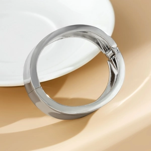Dettaglio di un bracciale a cerniera in argento lucido con finitura a specchio e design moderno