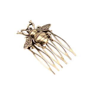 Detail shot of vintage bronze bee hair comb showing intricate wing patterns and textures