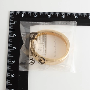 Dettaglio del bracciale dorato geometrico largo con chiusura e righello per misura