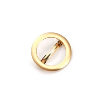 Detail view of a minimalist round gold hair clip with a sleek metallic brushed finish