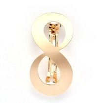 Detail view of infinity symbol hair clip with matte gold brushed metal texture and spring clasp