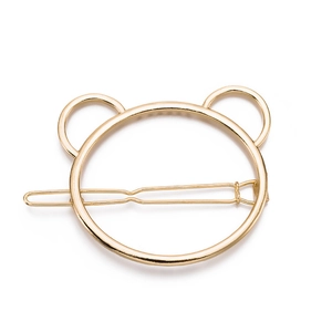 Detail of a minimalist golden bear-shaped metal hair clip with a sleek polished finish