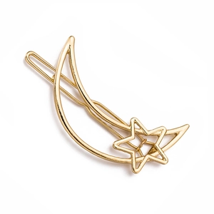 Detail view of a gold-toned minimalist alloy hair clip featuring moon and star designs