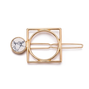 Detail of a geometric hair clip with gold metal finish and white marble stone inlay