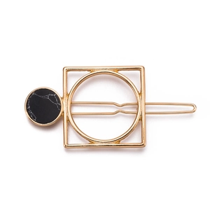 Detail of a gold geometric hair clip with a black marble textured circular inlay