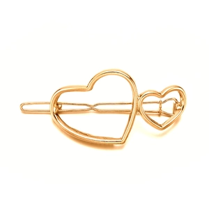 Close-up of golden hollow double heart hair clip with polished metallic finish