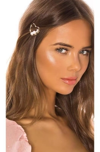 Detailed view of a gold heart hair clip with white pearls on a model's hair side