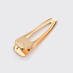 Detail of golden metal hollow hair clip featuring mirror finish and spring duckbill mechanism