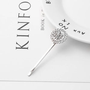 Macro shot of silver sunflower hair clip with sparkling rhinestones on a ceramic plate