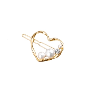 Detail of a golden heart hair clip with three white pearls and a sparkling rhinestone