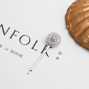 Silver alloy geometric sunflower hair clip with clear rhinestones on book pages