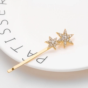 Barrette dorée ornée d'étoiles scintillantes en strass sur un plateau blanc chic