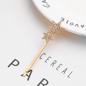 Pince à cheveux dorée avec étoiles en strass étincelants sur fond de magazine épuré