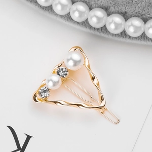 Detailed close-up of a golden wave triangle hair clip with pearls and crystals
