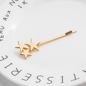 Close-up of golden alloy star hair clip on a minimalist white ceramic plate decor