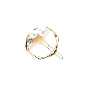 Detailed view of golden round hair clip with white pearls and sparkling rhinestone