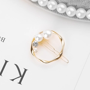 Macro detail of gold circle hair clip with pearls and rhinestones on a minimalist background