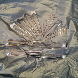Detail of U-shaped metal hairpins with pearls and cat ear shell inlays in various finishes