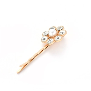 Detail of gold floral hair clip featuring a white pearl and sparkling rhinestones