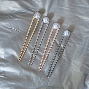 Detail view of four minimalist U-shaped metal hairpins with elegant white pearls in four colors