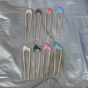 Close-up of 8-piece U-shaped hair pins in four glossy colors on a grey fabric surface