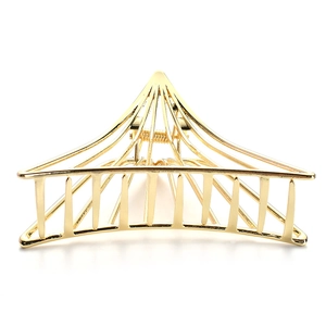 Close-up of golden geometric hollow triangle hair claw clip with metallic spring