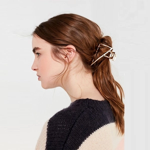 Golden geometric triangle hair claw clip for women shown on long brunette hair