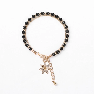 Detail of double-layer beaded bracelet with golden flower pendant and crystal accents