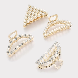 Detail view of four gold metal hair claws with inlaid pearls and sparkling rhinestones