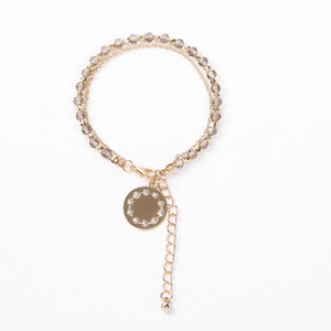 Detail of double-layer beaded bracelet with gold chain and round crystal charm