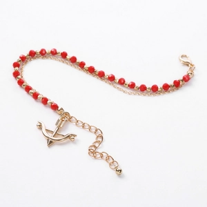 Detail of double-layer beaded bracelet with red faceted stones and golden arrow pendant