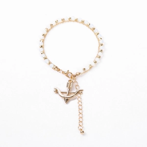 Detail of a double-layer bracelet with white beads and a golden bow pendant