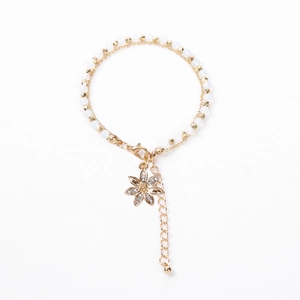 Detail of beaded layered bracelet with gold flower charm and sparkling crystal accents