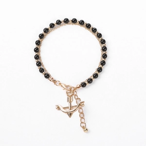 Detail of beaded bracelet with black shiny beads, gold chain, and arrow charm detail