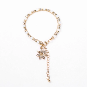 Close-up of double-layer beaded bracelet featuring a gold flower pendant with crystals