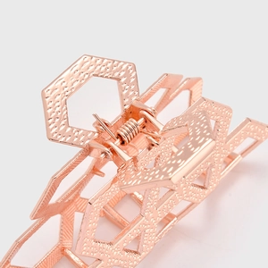 Détail d'une pince à cheveux hexagonale en or rose avec maille creuse et texture martelée