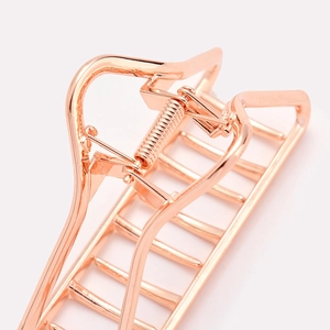 Vue macro d'une pince à cheveux géométrique en métal or rose au fini poli