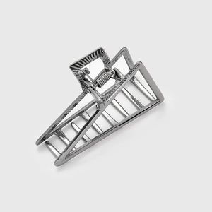 Macro detail of silver geometric hollow hair claw clip with strong metal spring