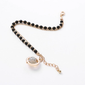 Detail of double-layer beaded bracelet with gold planet charm and black crystal beads