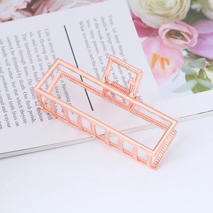 Detail of rose gold rectangle metal hair claw clip on lifestyle magazine background