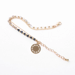 Detail of double-layer beaded bracelet with a round crystal pendant and gold-plated chain