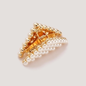 Macro shot of gold metal hair claw clip featuring tiered white faux pearl embellishments
