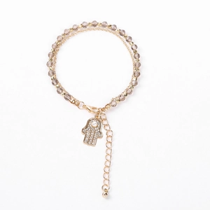 Macro detail of Hamsa Hand charm with crystals and beaded multi-layer bracelet