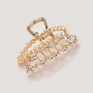 Detailed macro view of golden metal hair claw clip with pearls and sparkling rhinestones