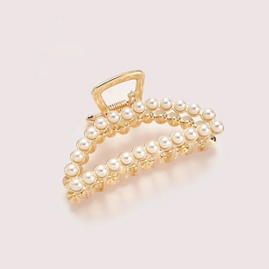 Detailed macro view of a gold-plated alloy hair claw clip with double rows of pearls