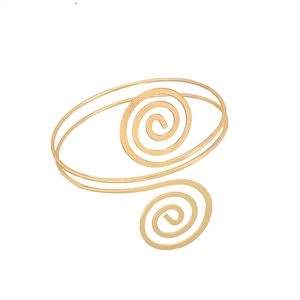 Dettaglio del bracciale da braccio a spirale dorato con texture metallica minimalista
